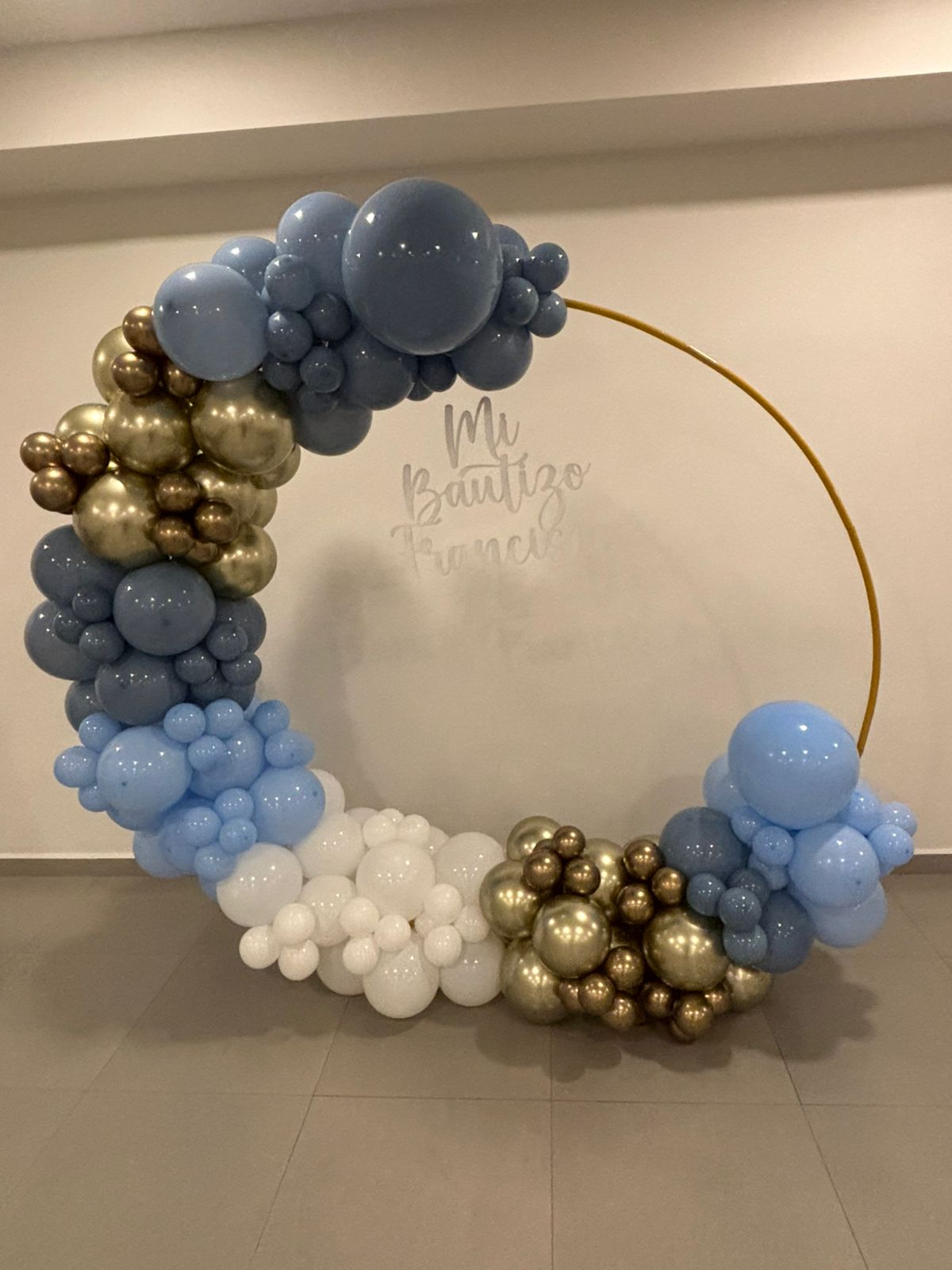 Aro de globos en tonos azul, blanco, dorado y cromado para bautizo