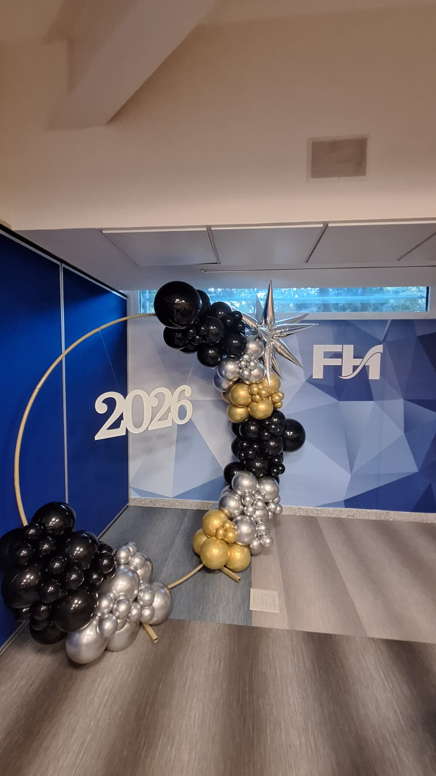 Aro de globos en tonos azul, dorado, negro y cromado para evento corporativo