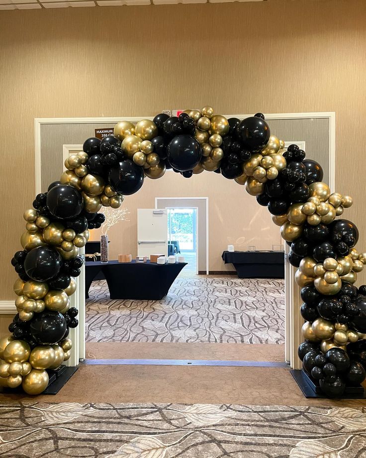 Arco de globos en tonos dorado, negro y cromado para evento