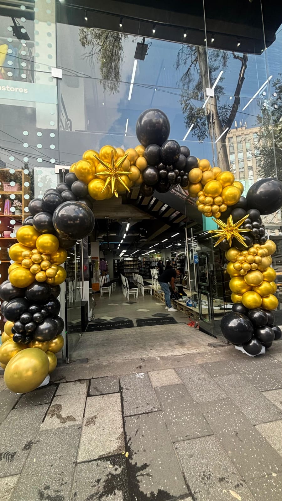 Arco de globos en tonos dorado, negro y cromado para evento corporativo