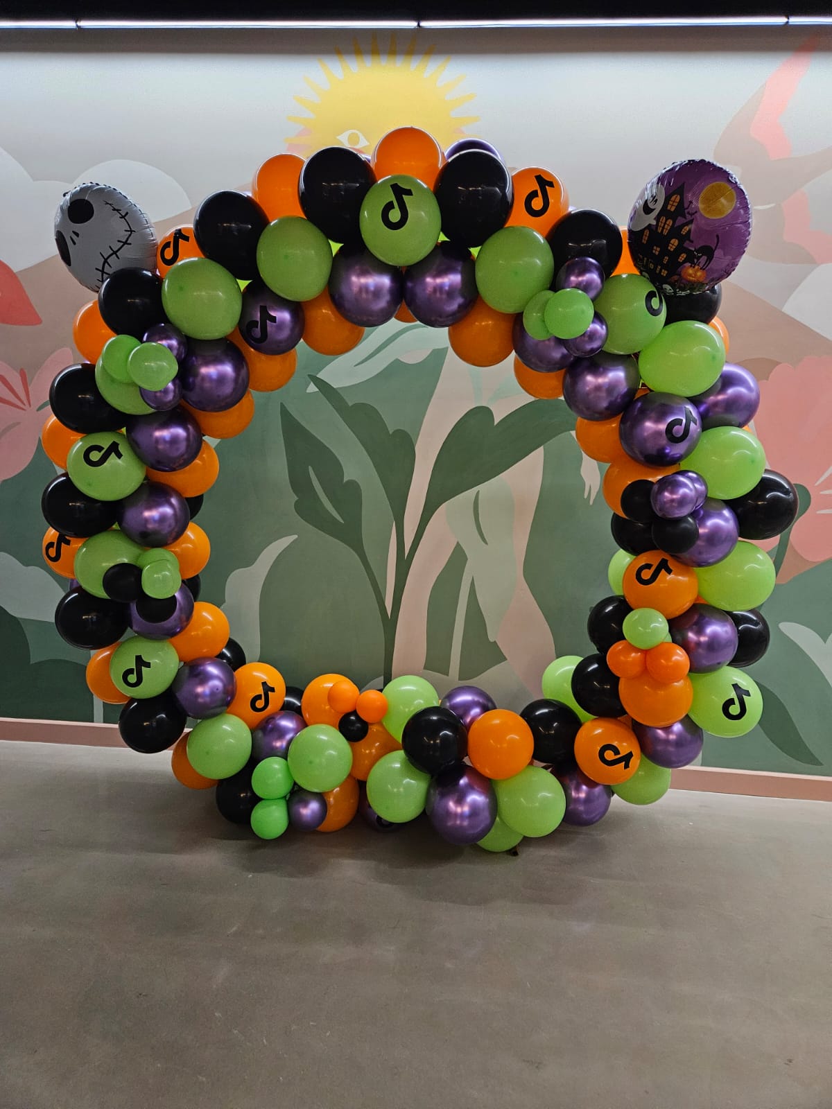 Aro de globos morado, verde y negro con flores para evento - Perfect Party