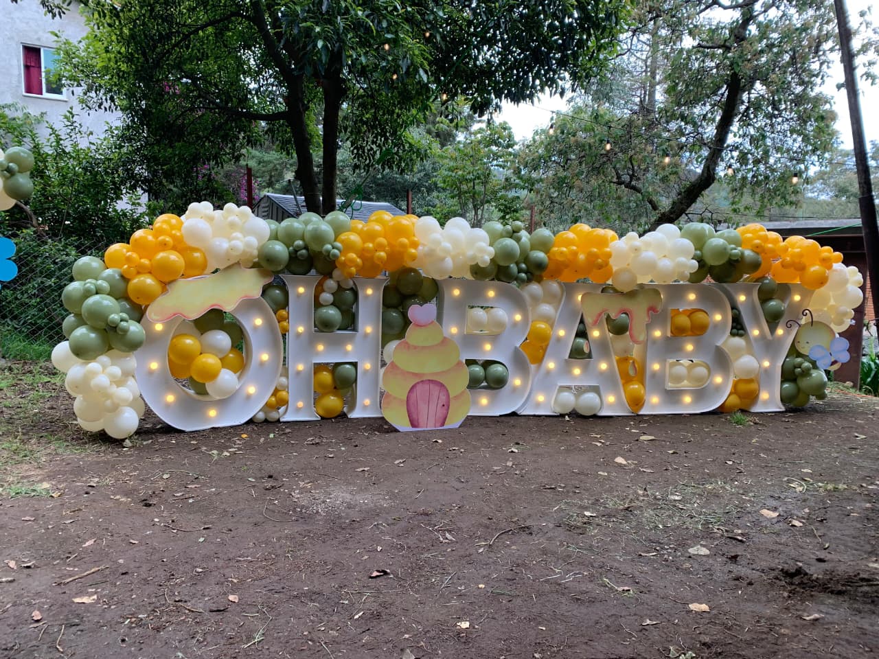 Decoración con globos blanco crema, verde y amarillo con letrero Oh Baby y letras LED para revelación de género - Perfect Party