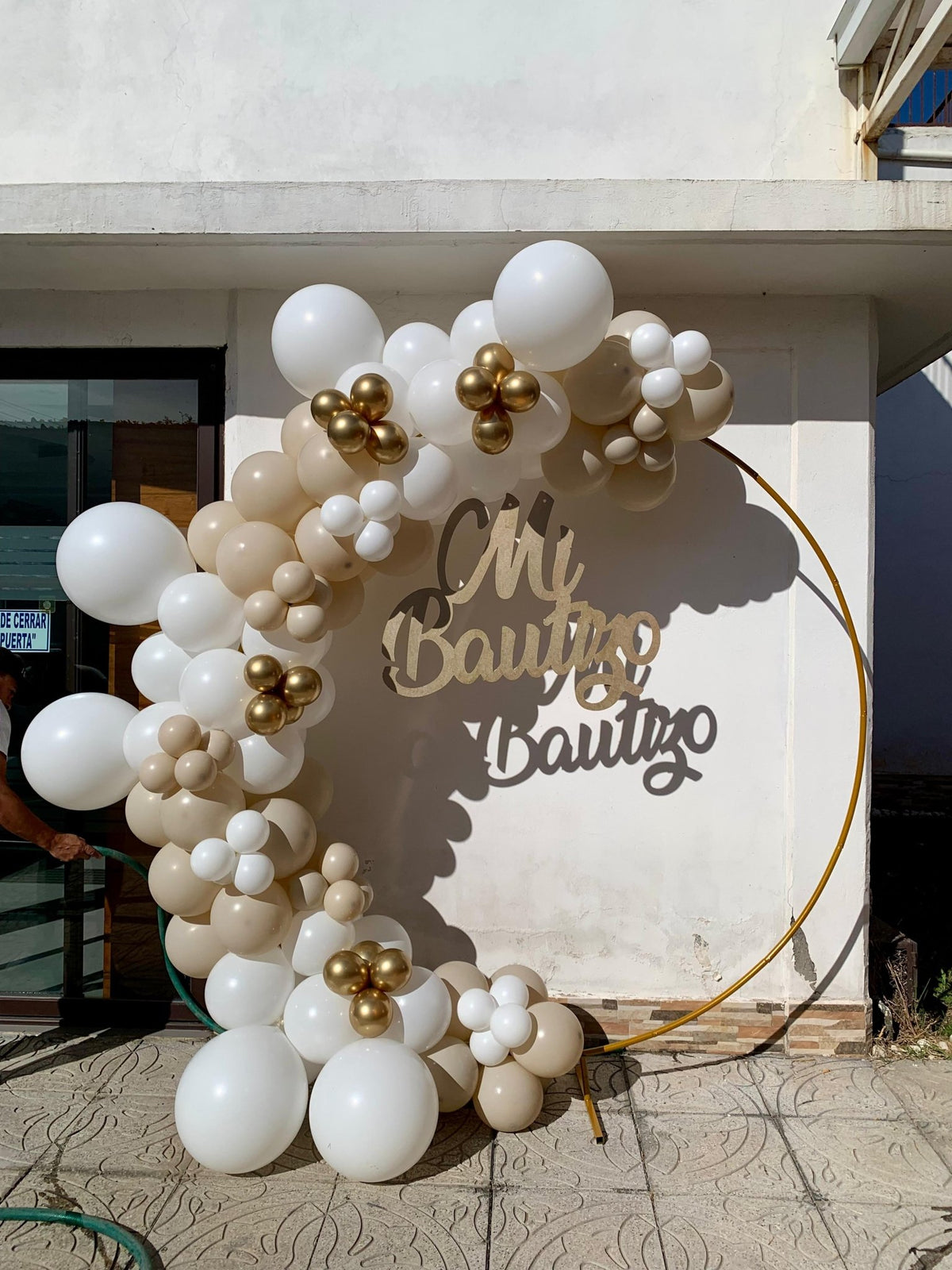 Aro De Globos Blanco Beige Y Dorado Con Letrero Mi Bautizo En Exterior aro-de-globos-blanco-beige-y-dorado-con-letrero-mi-bautizo-en-exterior